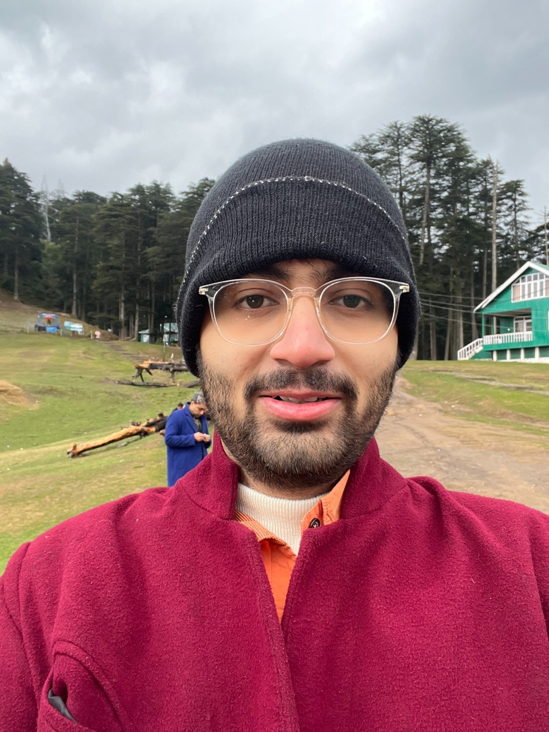 Dhruv taking an outdoor selfie in a beanie and red jacket